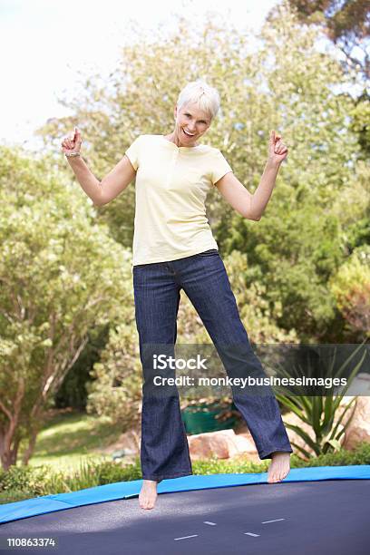 Senior Woman Jumping On Trampoline In Garden Stock Photo - Download Image Now - Trampoline - Equipment, Women, One Woman Only