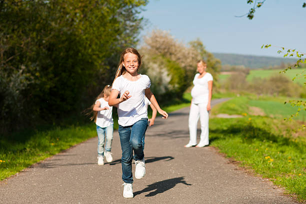 istock kids running down a path, pregnant mother standing 110875581