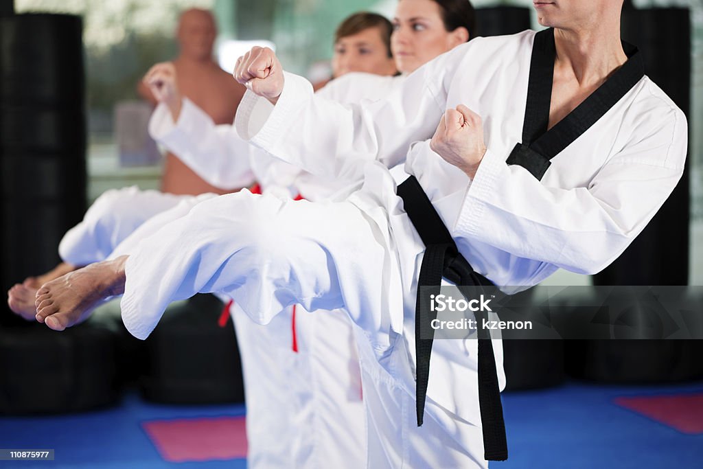 Martial Arts sport training in gym People in a gym in martial arts training exercising Taekwondo, the trainer has a black belt Taekwondo Stock Photo