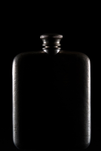 Dark hip-flask shining isolated on black background.