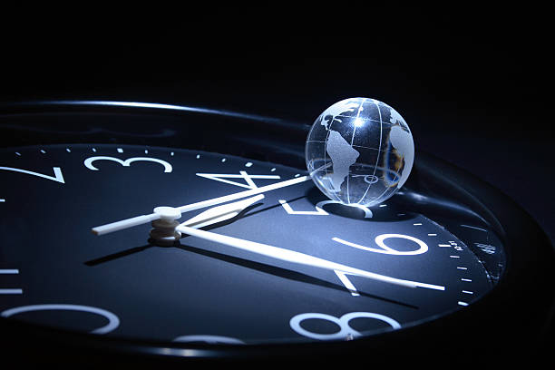 World globe resting on clock showing time stock photo