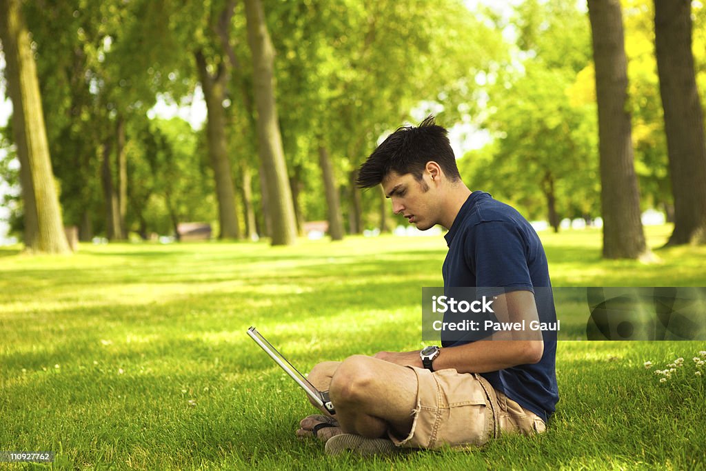 Mężczyzna studentów robi Praca domowa na laptopa na zewnątrz - Zbiór zdjęć royalty-free (Dorosły)