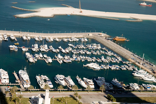 Aerial bird's eye view of Zygi fishing village port, Larnaca, Cyprus. The fish boats moored in the harbour with docked yachts and skyline of the town near Limassol from above.