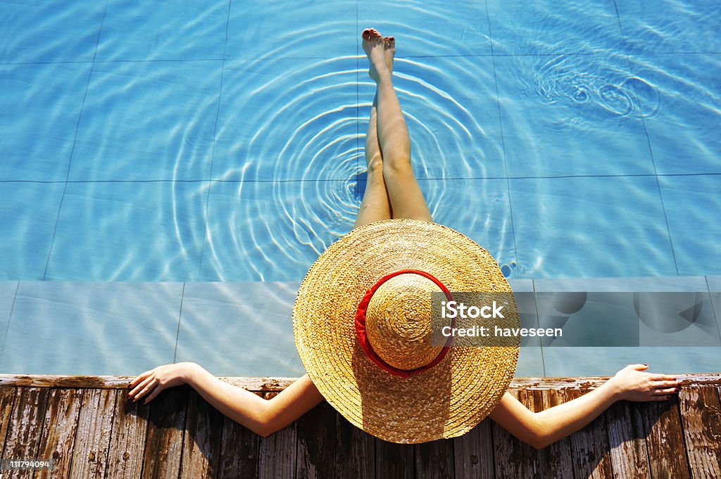 Woman wearing hat and relaxing poolside  Hat Stock Photo