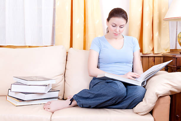 istock Charming woman reading  book sitting on a sofa 111811894