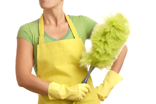Woman with green feather duster for spring cleaning 