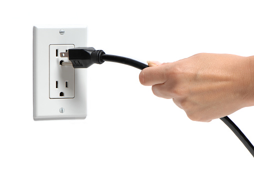 Woman's Hang Pulling Plug Out of Socket on White