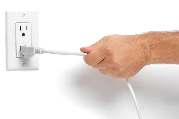 мужчина рука, потянув's электрический шнур подключения с замком на белом - electric plug outlet pulling electricity стоковые фото и изображения