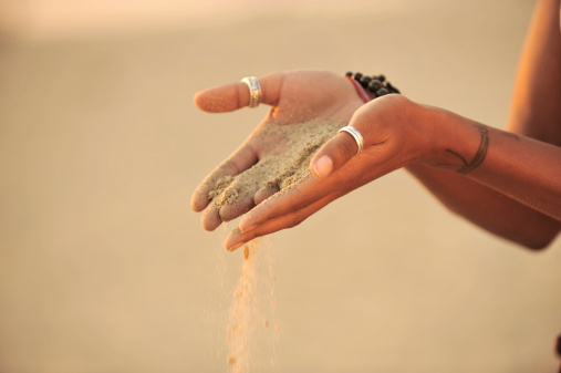 A young African American woman pours sand from her hands