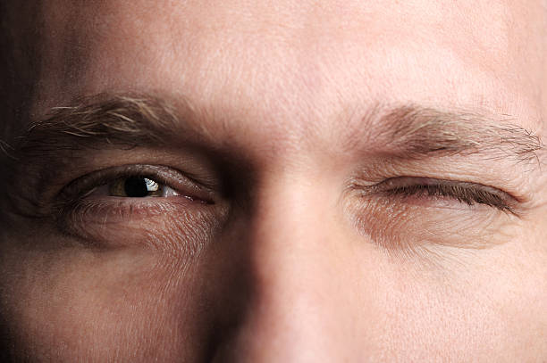 extreme close up hombre guiñar el ojo - parpadear fotografías e imágenes de stock