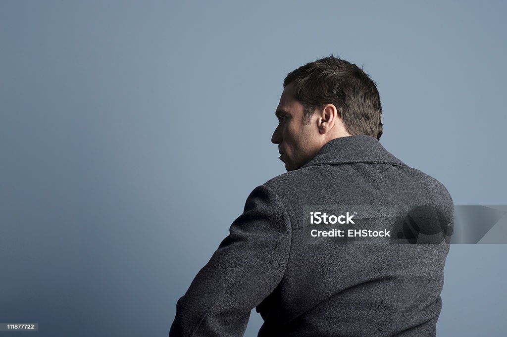 Homme en manteau d'hiver contre mur Gris bleu, vue de derrière - Photo de Hommes libre de droits