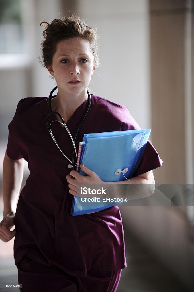 Emergency Room Nurse Running Redhead Doctor or Nurse Running down exterior hospital corridor with files in hand, slight motion blur Nurse Stock Photo
