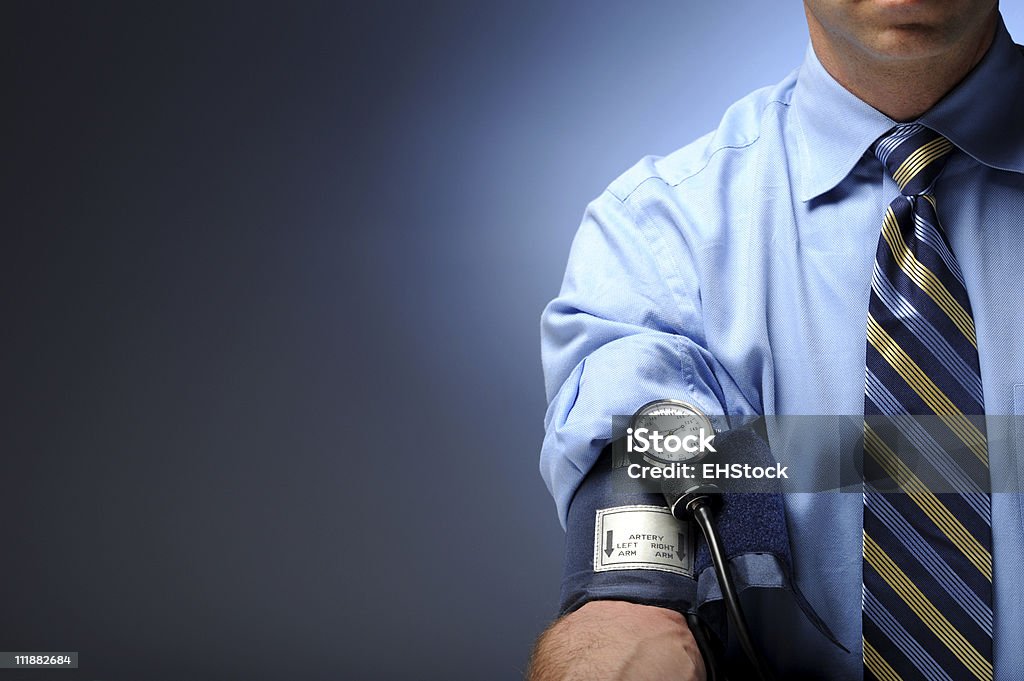 Uomo d'affari con il bracciale per la misurazione della pressione arteriosa sul braccio destro - Foto stock royalty-free di Misuratore di pressione sanguigna