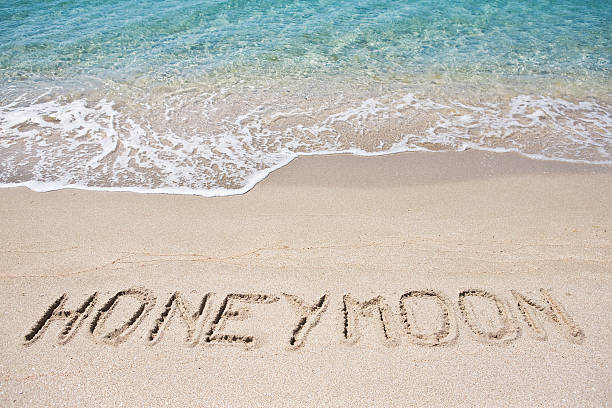 Honeymoon written on the sand stock photo
