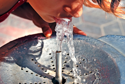 Outdoor drinking fountain made of stone with a silver tap