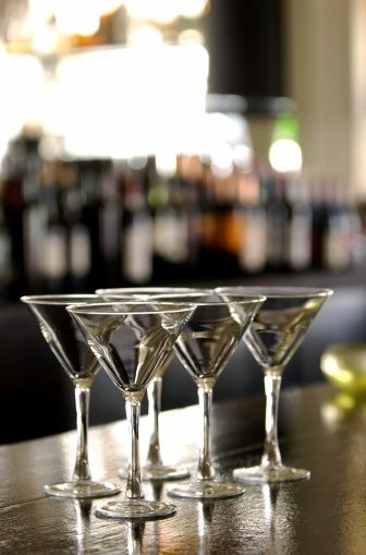 Five martini glasses arranged on the bar of a swank, hip, west hollywood club.