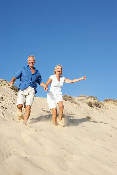 istock Senior Couple Enjoying Beach Holiday Running Down Sand Dune 111931138