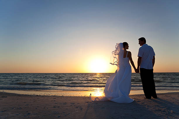 Bride & Groom Married Couple Sunset Beach Wedding Wedding of a married couple, bride and groom, together at sunset on a beautiful tropical beach beach wedding dress stock pictures, royalty-free photos & images