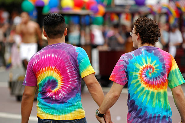 gay para trzymając się za ręce w tęczy koszulki tie-dye - gay man homosexual sex men zdjęcia i obrazy z banku zdjęć