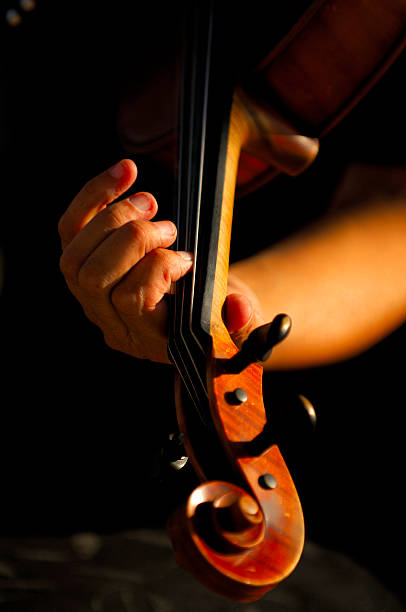 istock Woman's Hand Fingering Violin Neck Scroll Tuning pegs on Black 111949460