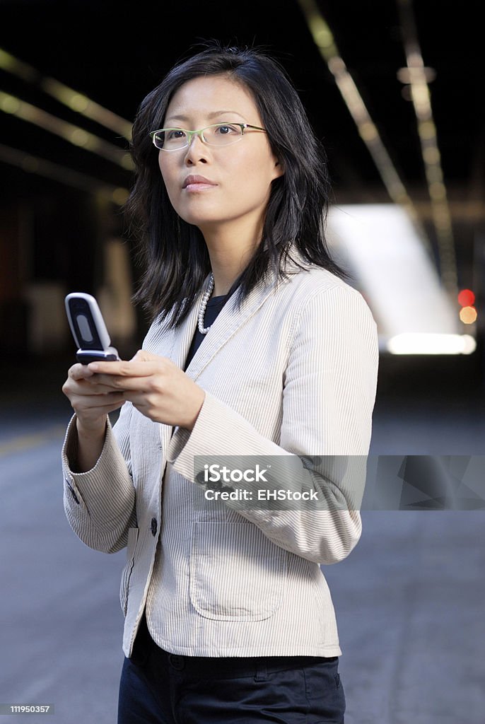 Young Asian Businesswoman Texting on Mobile Device A young Asian woman in business wear sends a text message on her mobile phone 20-24 Years Stock Photo