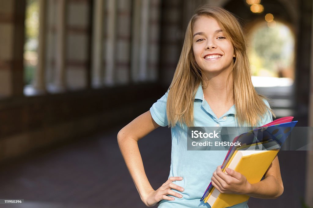10 代の女子学生、腰に手を当てる保持書籍のキャンパス - 1人のロイヤリティフリーストックフォト