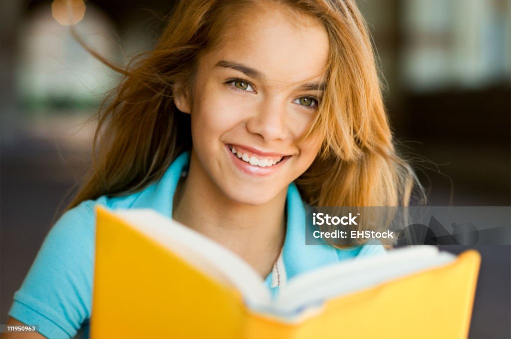 Adolescente sonriente niña en edad escolar con libro en la escuela Campus - Foto de stock de Niña en edad escolar libre de derechos