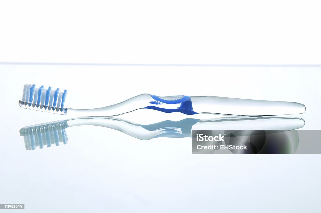 Spazzolino in plastica trasparente sulla superficie riflettente - Foto stock royalty-free di Spazzolino da denti