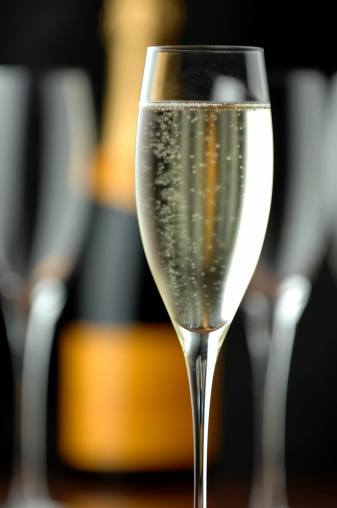 Glass of green champagne with ice on white background