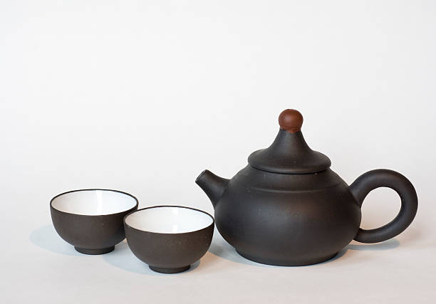 istock A small black Chinese tea pot with two cups on white back. 111954509