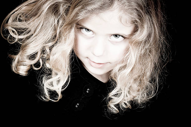 Closeup portrait of beautiful smiling Caucasian blonde girl with long hair on light neutral beige background. Pretty real girl child with natural emotions. Happy authentic childhood lifestyle.