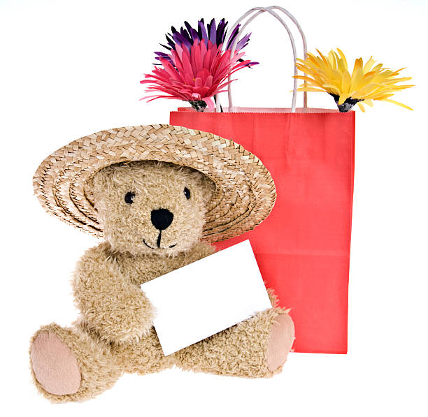 Cute teddy bear sitting on hat with flower