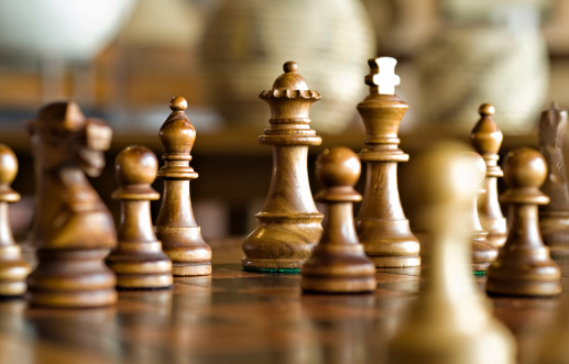 Wooden light and dark chess pieces stand on the board. Chess isolated on a white background. A game for the development of tactics, intelligence, leadership skills. Game and Business strategy.