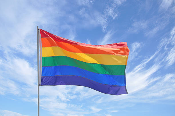 istock Gay Pride Flag Pole Waving in Blue Cloudscape Sky 112035664