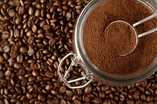 Ground coffee in jar on coffee beans.