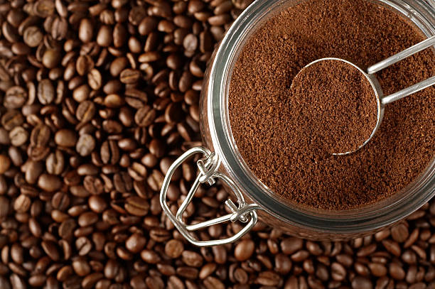 Close up of many whole coffee beans and ground coffee beans Ground coffee in jar on coffee beans. ground coffee stock pictures, royalty-free photos & images