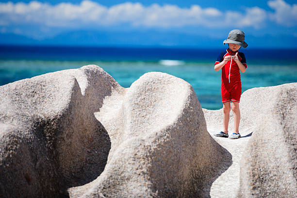 Cute little African boy playing with toy cars in the sand during a trip to the beach in summer