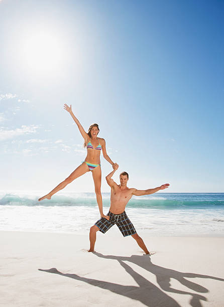 человек, поддерживая подругу в его ноги на пляже - shirtless beach women bikini стоковые фото и изображения