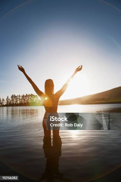 Donna In Piedi In Un Lago Con Le Braccia Sollevate - Fotografie stock e altre immagini di Lago - Lago, Nuoto, Donne