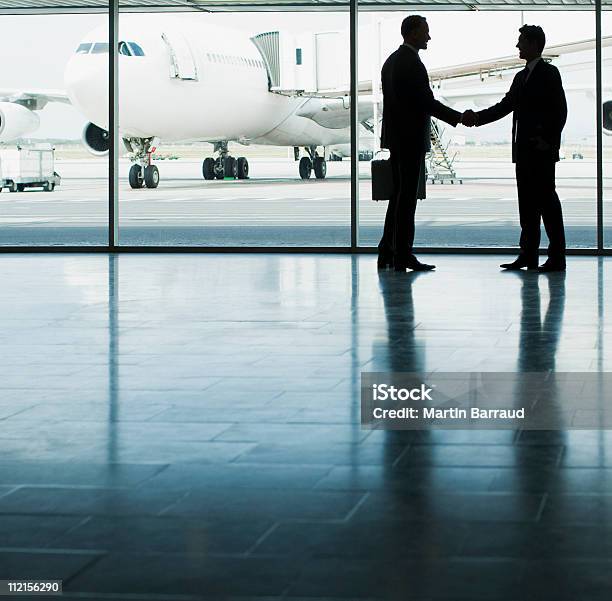 Hombres De Negocios Estrechándose Las Manos En El Aeropuerto Foto de stock y más banco de imágenes de Industria aeroespacial
