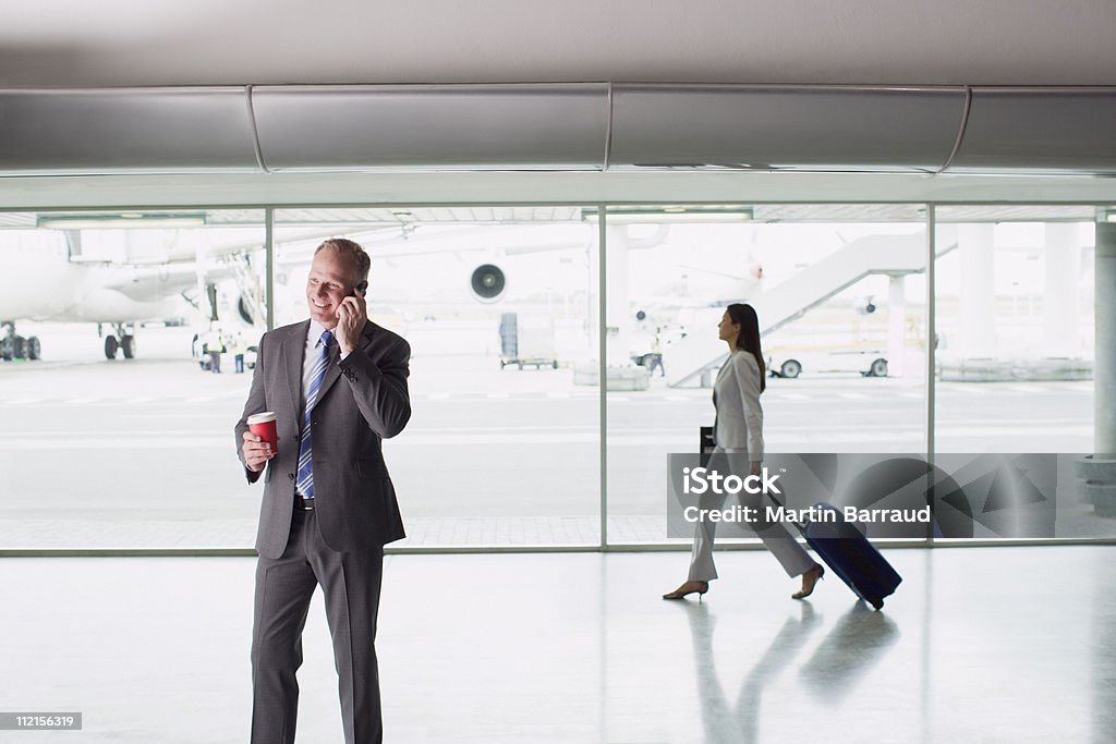 Uomo d'affari parlando sul cellulare in aeroporto - Foto stock royalty-free di Aeroporto