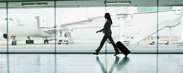 femme d'affaires avec des bagages à l'aéroport - business travel photos et images de collection