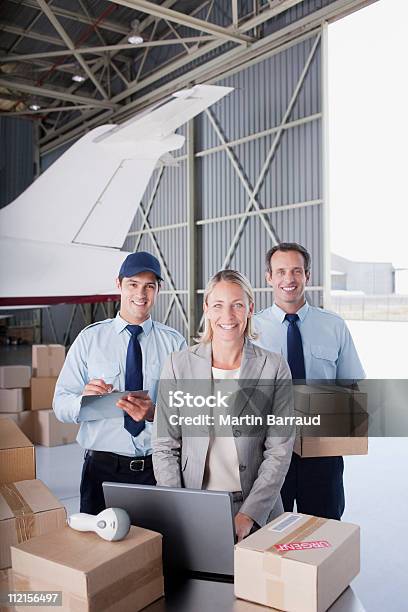 Supervisor Y De Los Trabajadores De Pie Con Cajas En El Hangar Foto de stock y más banco de imágenes de Oficio