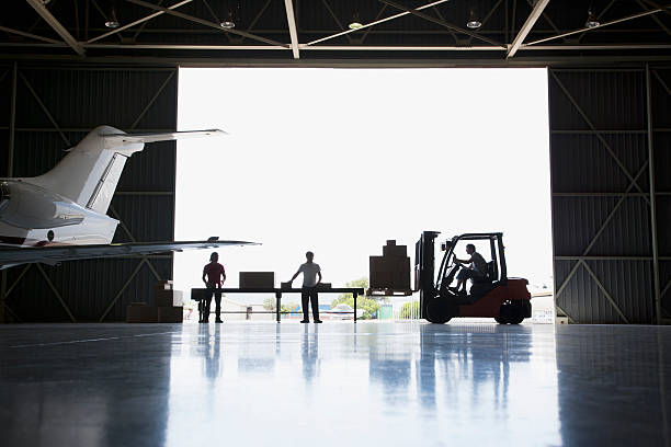 travailleurs boîtes et chariot élévateur en hangar - airport airplane freight transportation transportation photos et images de collection
