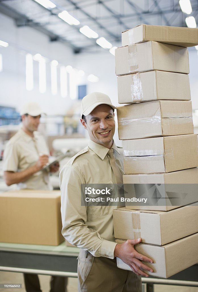 Worker carrying stack of boxes in shipping area  Mail Stock Photo