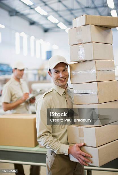 Worker Carrying Stack Of Boxes In Shipping Area Stock Photo - Download Image Now - Mail, Occupation, Smiling