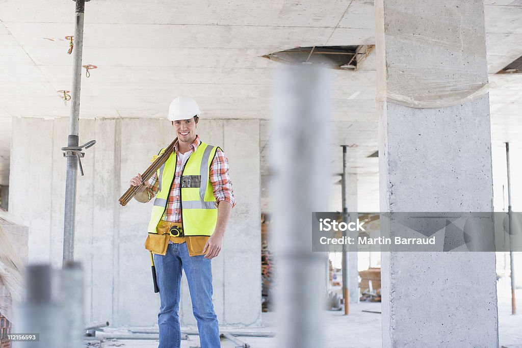 Trabajador de la construcción en sitio de construcción de pie - Foto de stock de Trabajador de construcción libre de derechos