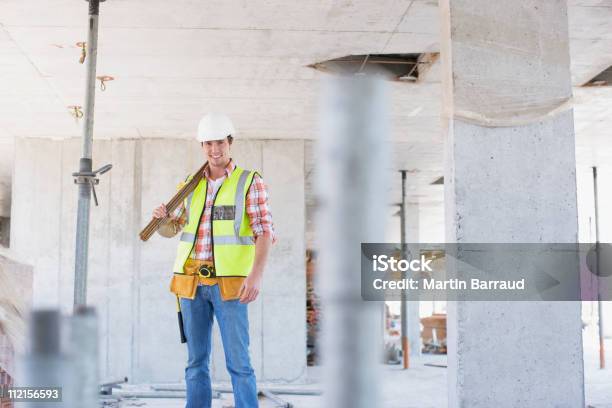 Trabajador De La Construcción En Sitio De Construcción De Pie Foto de stock y más banco de imágenes de Trabajador de construcción