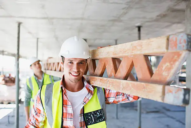 Photo of Construction worker carrying girder on construction site