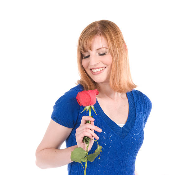 Close-up shot of a woman holding and smelling a freshly picked rose. Early morning in the garden.